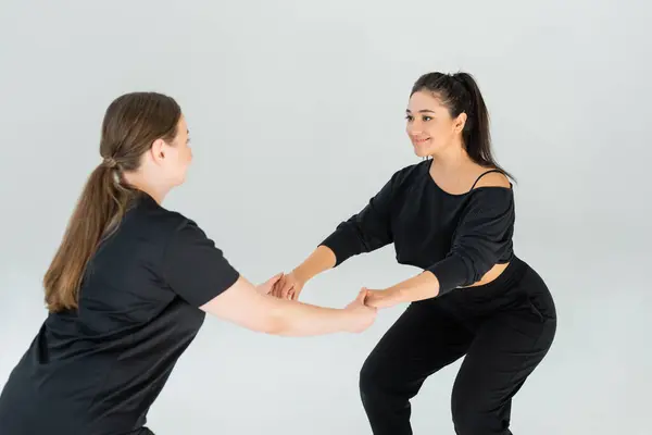 Two women engaged in a fitness activity, showcasing camaraderie and support while exercising. — Stock Photo