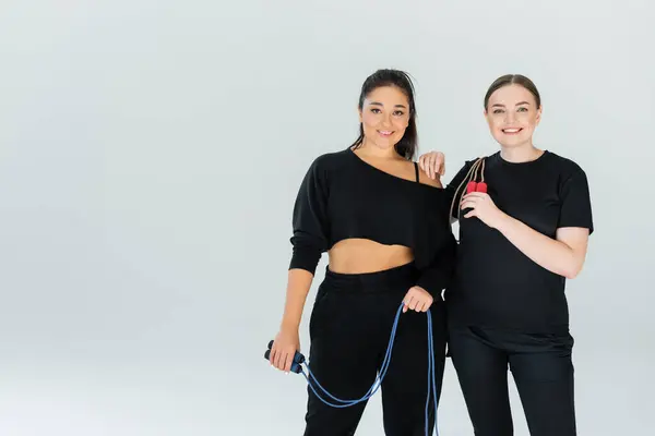 Two strong and beautiful women enjoy a dynamic moment in their fitness journey while smiling. — Stock Photo
