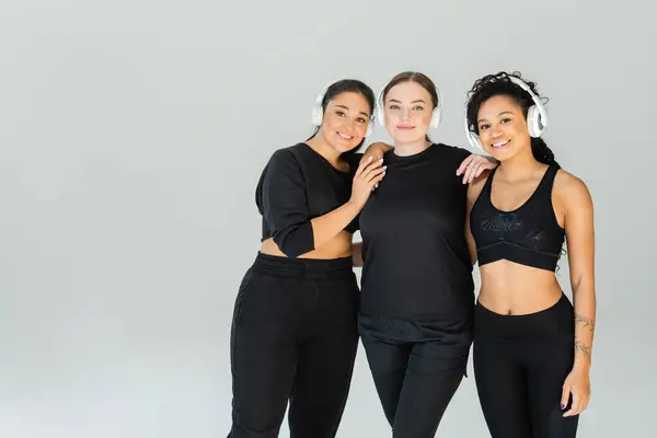 Three fit and strong women share smiles in a fitness studio while wearing stylish sportswear. — Stock Photo
