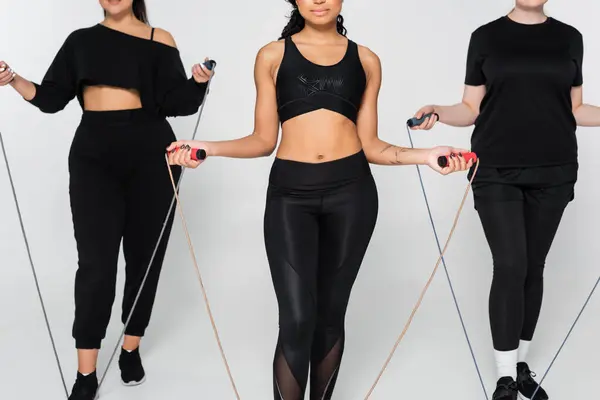 Three confident women in stylish sportswear skip ropes, showcasing their strength and diversity. — Stock Photo