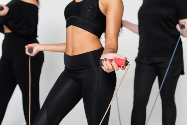 Three fit women use jump ropes for strength in a stylish gym. — Stock Photo