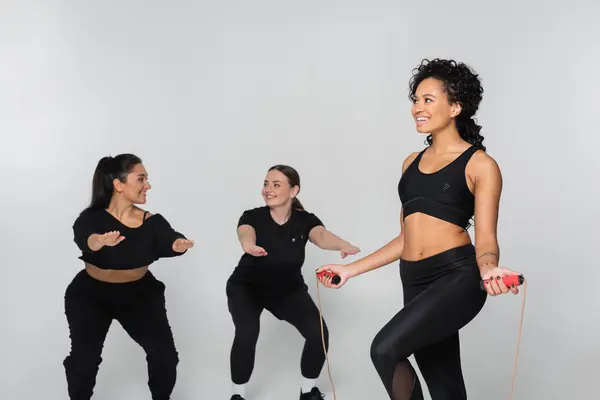 Three women showcase strength and teamwork while exercising with jump ropes in sleek outfits — Stock Photo