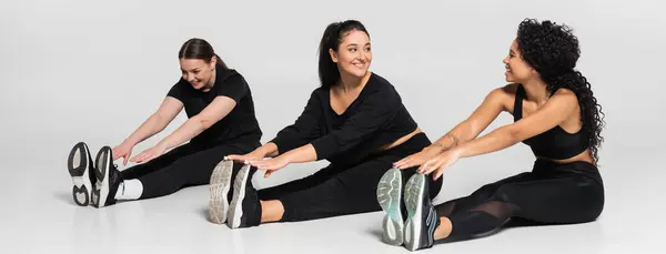 Des femmes fortes et en forme s'engagent dans une routine d'étirement, mettant en valeur leur athlétisme et leur unité. — Photo de stock