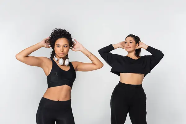 Deux femmes fortes et en forme mettent en valeur leur athlétisme tout en portant des vêtements de sport élégants dans un studio. — Photo de stock