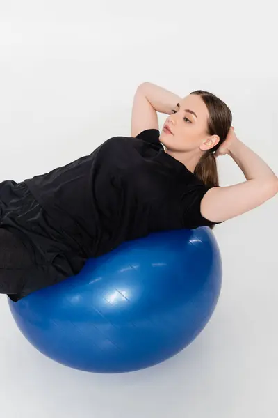 A female athlete strength trains on a blue stability ball, highlighting her fitness and dedication. — Stock Photo