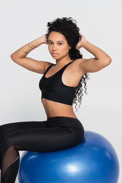 Strong and fit woman confidently poses on a blue stability ball, celebrating athleticism and beauty. — Stock Photo