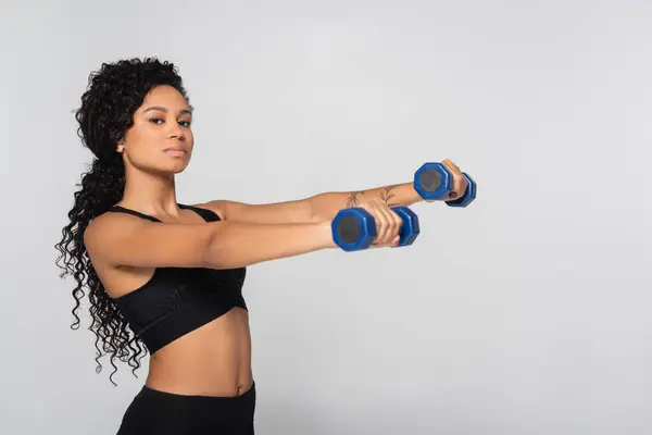 Una mujer en forma realiza entrenamiento de fuerza con pesas en un espacio de fitness moderno y bien iluminado. - foto de stock