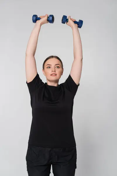 Woman showcases strength and determination while lifting dumbbells during a workout session — Stock Photo