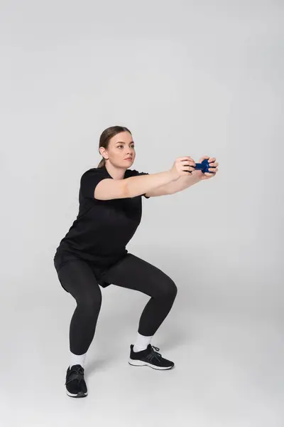 A woman squats with a fitness tool, demonstrating her strength and commitment to fitness. — Stock Photo