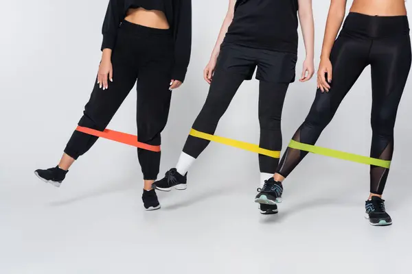 Three strong women showcase their fitness strength while using resistance bands for a workout. — Stock Photo