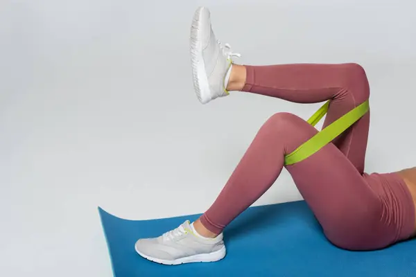 Strong woman engages in a leg workout using a resistance band, showcasing her fitness routine. — Stock Photo