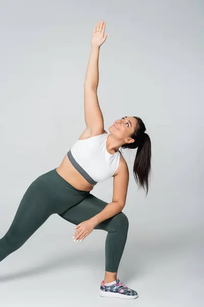 A strong and beautiful woman engages in an elegant side stretch in a fitness studio during daylight. — Stock Photo