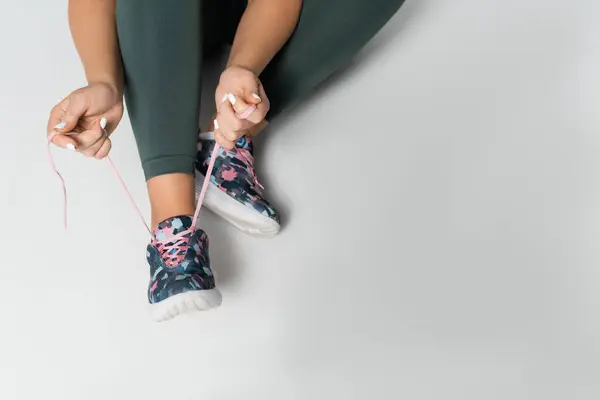 Une femme forte prépare ses chaussures, en se concentrant sur la tâche avant une routine de remise en forme difficile. — Photo de stock