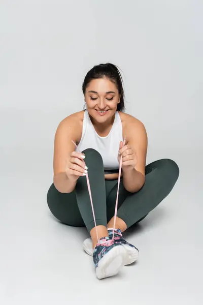 A strong female enjoys her workout while stretching resistance bands and smiling with joy. — Stock Photo