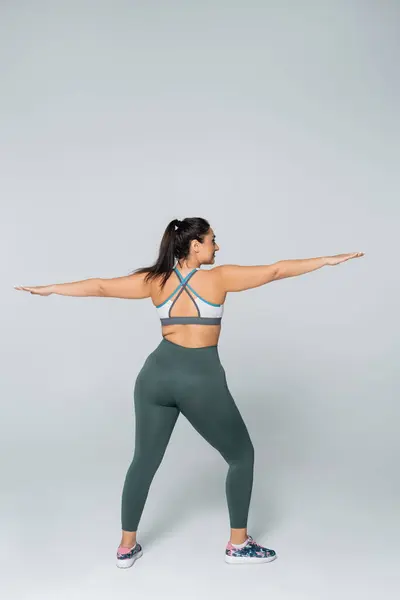 Eine selbstbewusste Frau nimmt eine kraftvolle Pose ein und betont Stärke und Athletik beim Training. — Stockfoto