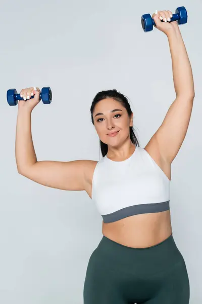 Una mujer fuerte se dedica a un entrenamiento dinámico, levantando pesas con confianza y gracia. - foto de stock
