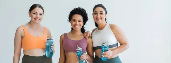 Three confident and fit women are celebrating their strength in a modern, well lit studio. — Stock Photo