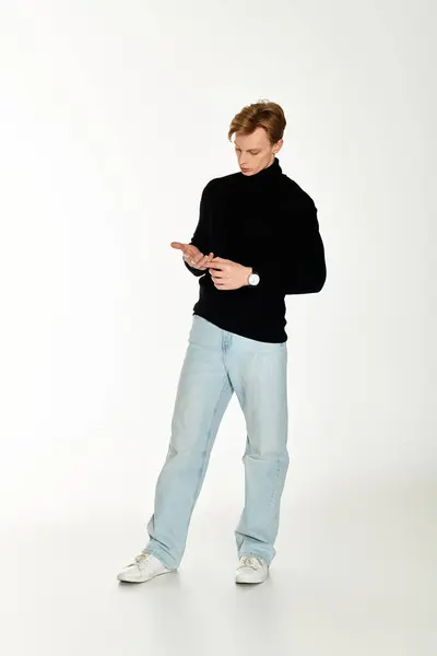 Un joven con estilo en ropa casual se centra en su teléfono inteligente en un estudio moderno. — Stock Photo