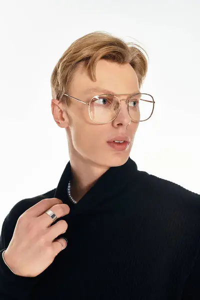 Young man with stylish glasses poses confidently, showcasing a trendy outfit and subtle expression. — Stock Photo