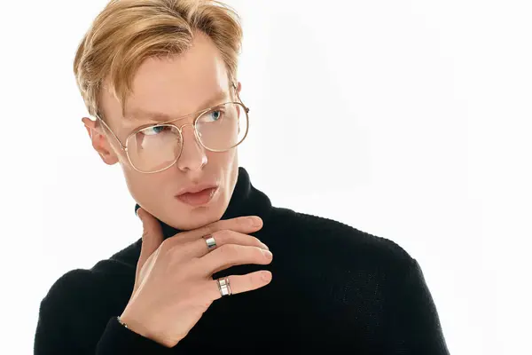 A stylish young man wearing glasses poses thoughtfully with a hand on his chin, exuding confidence. — Stock Photo