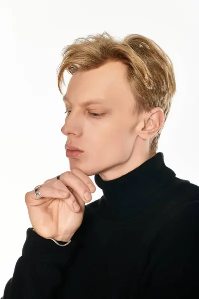 A striking young man contemplates deeply, showcasing his elegance in a sleek, modern room. — Stock Photo