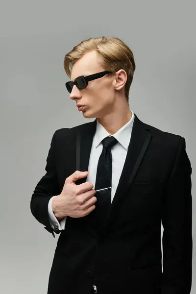 Junger Mann passt seine Krawatte an und präsentiert seinen stylischen Look in einem modernen Ambiente. — Stockfoto