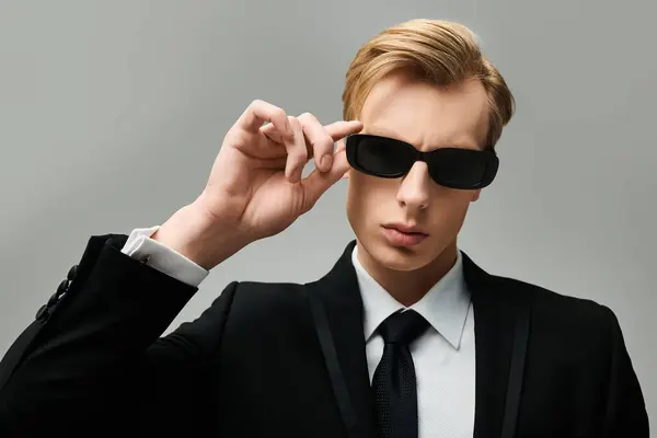 Striking young man wearing sunglasses and a suit exudes confidence in a minimalistic setting. — Stock Photo