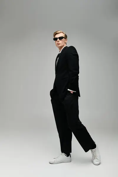 Young man stands confidently in a stylish suit and sunglasses, embodying contemporary elegance. — Stock Photo