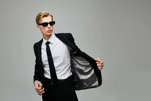 Молодой, красивый мужчина демонстрирует свой острый костюм и солнечные очки, источая харизму и стиль. — стоковое фото