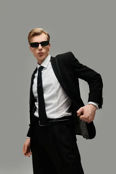 Im schicken Anzug und mit Sonnenbrille strahlt der junge Mann Charisma und Zuversicht aus. — Stockfoto