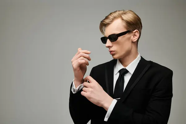 Confident young man in a tailored suit adjusting his cufflinks, exuding style and charm. — Stock Photo