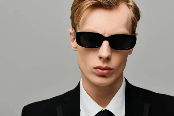 Young handsome man wearing sunglasses showcases a bold, confident expression in a chic setting — Stock Photo