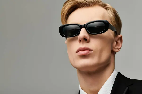 Charming young man with sleek hair models modern sunglasses with sophistication. — Stock Photo