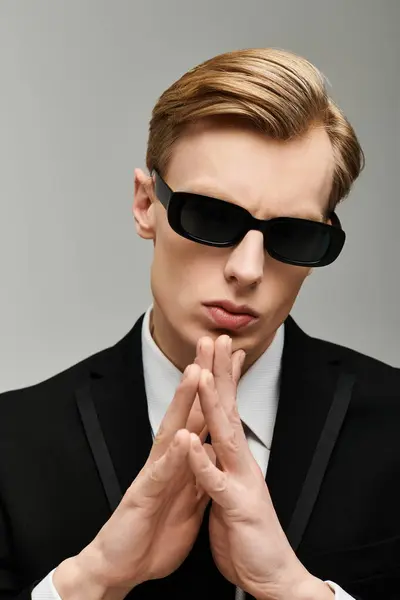 A confident young man dressed in a suit and sunglasses exudes charisma in a sleek setting. — Stock Photo