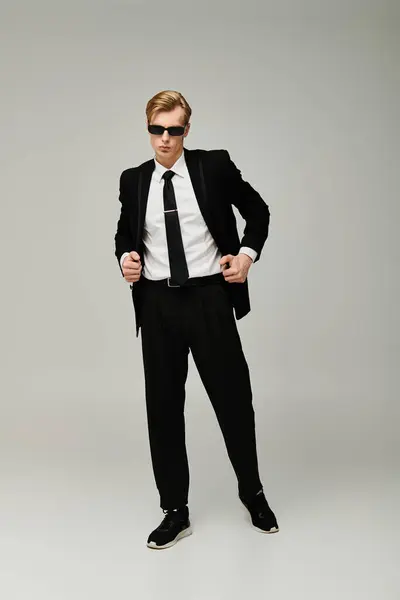 A young handsome man stands confidently in a stylish outfit, exuding charisma and charm. — Stock Photo