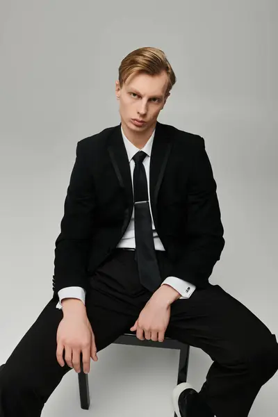 Stylishly dressed young man showcases a confident pose in an elegant studio environment. — Stock Photo