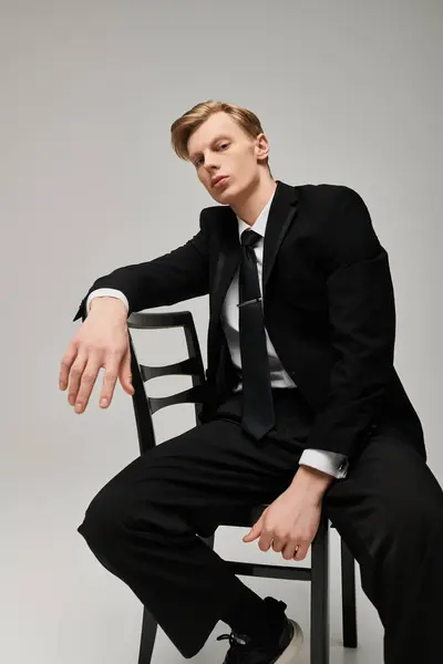 A young man in a stylish suit sits confidently in a chair. — Stock Photo