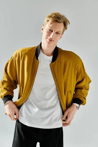 A handsome young man showcases a playful smile while adjusting his stylish jacket in a bright space. — Stock Photo