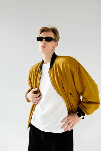 A young handsome man wears a stylish bomber jacket and sunglasses, showcasing his fashion sense. — Stock Photo