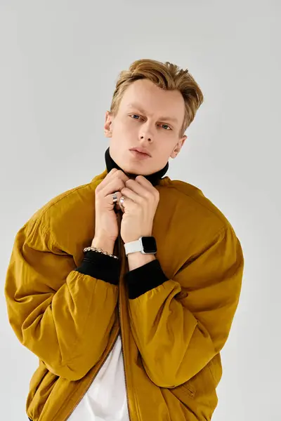 Confident young man presents trendy fashion with a stylish jacket while posing thoughtfully indoors. — Stock Photo