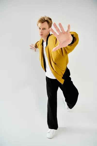 With confidence, a young handsome man strikes a dynamic pose, showcasing modern fashion choices. — Stock Photo