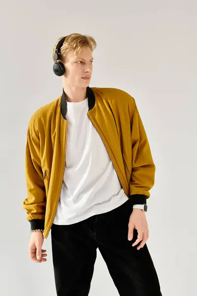 A young handsome man with headphones strikes a fashionable pose indoors, exuding confidence. — Stock Photo