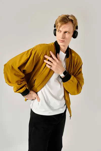 Handsome young man wearing a trendy jacket and headphones exudes charisma in a chic studio. — Stock Photo