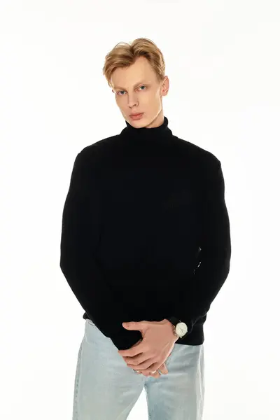 A young handsome man stands confidently, showcasing his fashion sense in a sleek black turtleneck. — Stock Photo