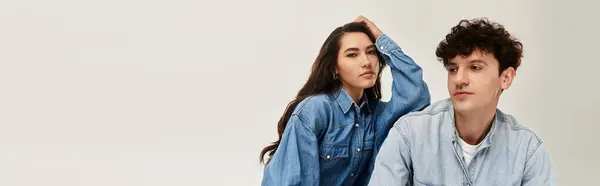 Una joven pareja posa elegantemente en traje de mezclilla de moda, encarnando sensibilidades de moda moderna. - foto de stock