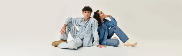 A fashionable duo sits on a clean, light backdrop, exuding youthful energy and style. — Stock Photo