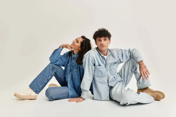 Two young fashion lovers showcase their unique styles in trendy denim against a neutral backdrop. — Stock Photo