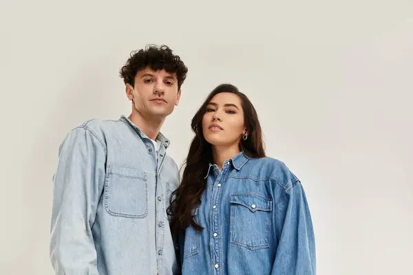 Stylish young duo poses confidently in matching denim outfits against a neutral backdrop. — Stock Photo
