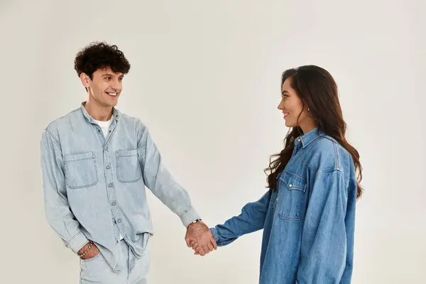 A trendy young couple smiles and holds hands, exuding style and creativity. — Stock Photo