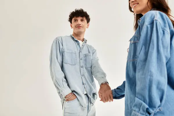 Two young individuals dressed in trendy denim outfits connect in a contemporary, stylish atmosphere. — Stock Photo